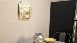 Una mesa de comedor con dos platos amarillos, un florero de vidrio transparente y un adorno de pared.