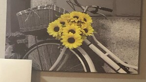 Un cuadro colgado en la pared que muestra una bicicleta con girasoles.