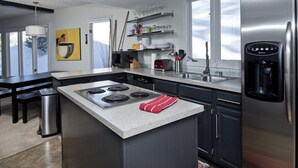 Ett modernt kök med en central köksö, rostfria vitvaror och en inbyggd vattendispenser.