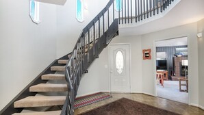 En trappa med beige, mattbeklädda trappsteg och ett svart räcke, som leder upp till en vit dörr med en dekorativ glaspanel.