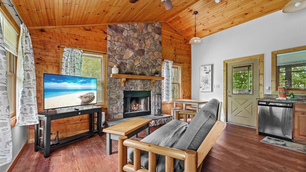 Un acogedor interior de cabaña con chimenea de piedra, muebles de madera y un televisor.
