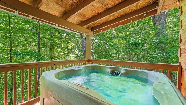 A hot tub on a wooden deck with a view of a forest.