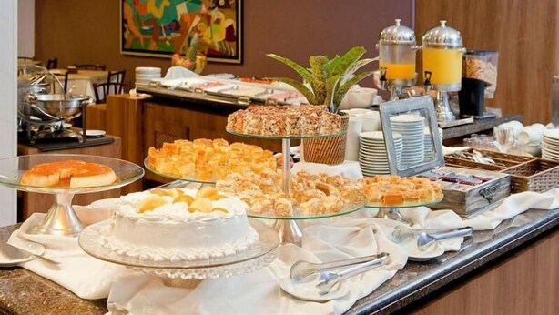 A buffet with various desserts and beverages, including a cake, pastries, and fruit.