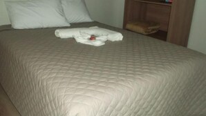 A neatly made bed with a quilted bedspread, two pillows, and a folded towel on the bed.