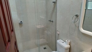 A bathroom with a glass-enclosed shower, a toilet, and a sink.