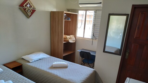 A bedroom with two beds, a wardrobe, a desk, and a mirror.