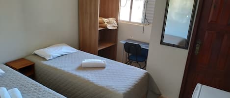 Un dormitorio con dos camas, un armario, un escritorio y un espejo.
