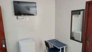 A small room with a desk, chair, and a television mounted on the wall.