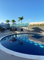 Zona de piscina en la azotea con vistas despejadas al océano, rodeada de sillones de descanso y sombrillas.
