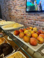 Un bufé con diferentes opciones de comida, incluyendo manzanas, un pastel de chocolate y otros postres.