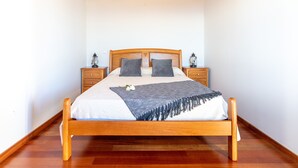 A wooden bed with a white and gray bedspread, two nightstands with lanterns, and a wooden floor. - Raivinha Mother House, A traditional home in the heart of Arco da Calheta (Arco da Calheta, Madeira)