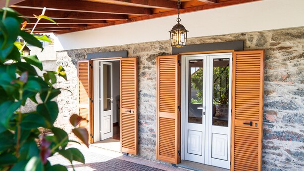 A stone building with wooden shutters and a hanging lantern. - Raivinha Mother House, A traditional home in the heart of Arco da Calheta (Arco da Calheta, Madeira)