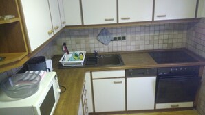 A compact kitchen with white cabinets, a wooden countertop, a dishwasher, and a stove. - 'Klein und Fein' Garbenteich (Pohlheim)