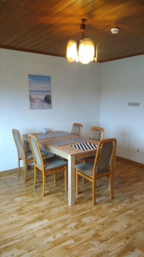 A dining area with a wooden table and chairs, a ceiling light fixture, and a wall-mounted picture. - 'Klein und Fein' Garbenteich (Pohlheim)