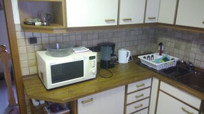 A kitchen with a microwave, coffee maker, and a basket of dishes. - 'Klein und Fein' Garbenteich (Pohlheim)