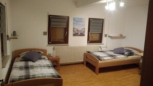 A bedroom with two wooden beds, a radiator, and two windows with blinds. - 'Klein und Fein' Garbenteich (Pohlheim)