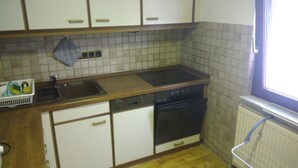 A kitchen with white cabinets, a black stove, and a dishwasher. - 'Klein und Fein' Garbenteich (Pohlheim)