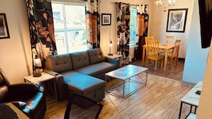 Ein modernes Wohnzimmer mit Sofa, Couchtisch und Essbereich.