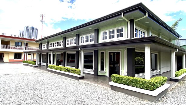 A two-story building with a covered entrance and a parking area in front. - Prado Inn & Suites (San José)