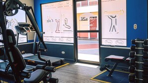 A gym with exercise equipment, a treadmill, and a bench. - Prado Inn & Suites (San José)