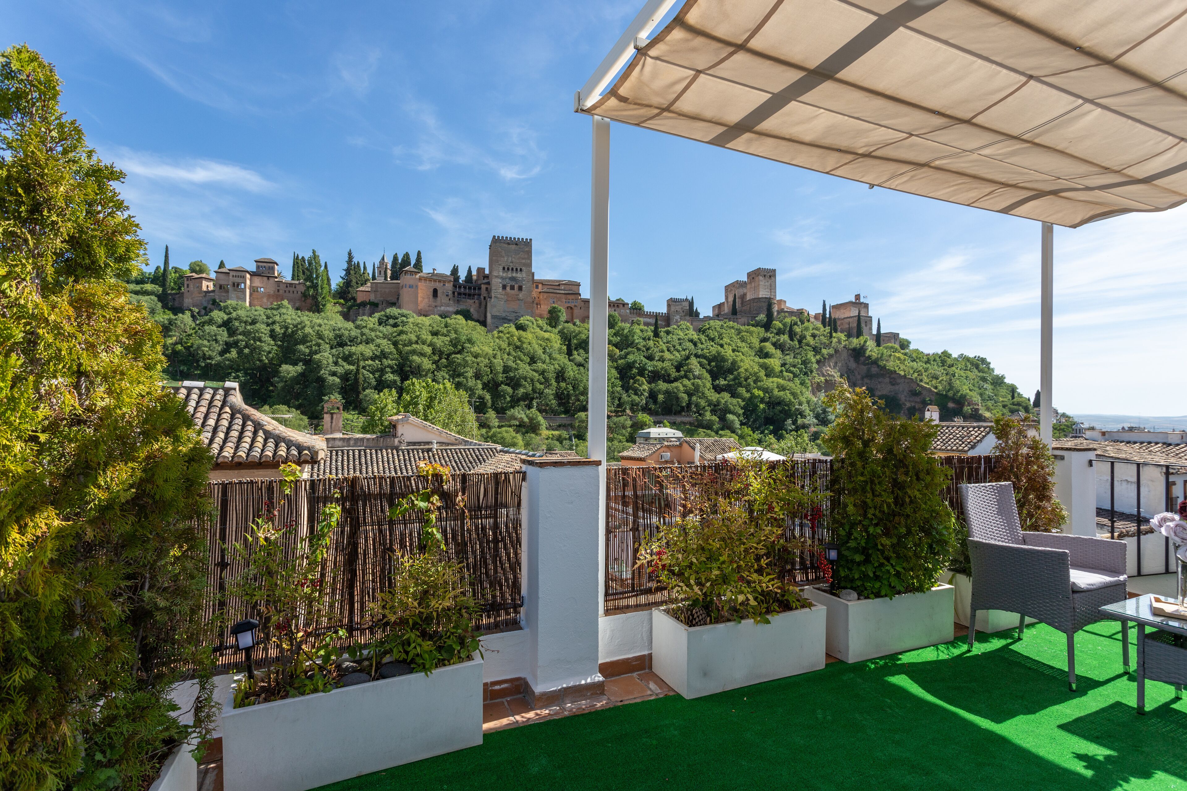 Terraza en la azotea con vistas a un castillo histórico, paredes blancas y césped artificial verde.