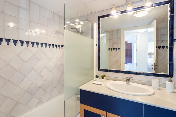 A bathroom with a large mirror, a sink, and a shower.