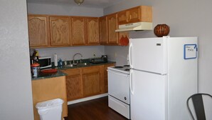 Una cocina con armarios de madera, un refrigerador blanco, una estufa y un microondas.