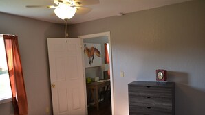 Un dormitorio con cama, cómoda, ventilador de techo y puerta que da a otra habitación.