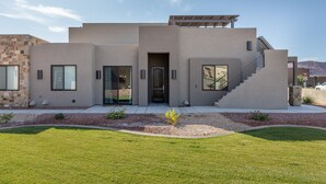 Een modern huis met een plat dak, een overdekte trap en een voordeur.