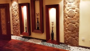 Un pasillo con paneles decorativos en la pared, piso de madera y un sendero de guijarros blancos.
