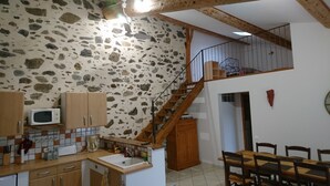 Eine Küche mit Steinwand, Holzschränken, einer Mikrowelle und einem Essbereich mit Tisch und Stühlen.