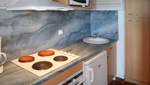 Uma cozinha compacta com micro-ondas, fogão e pia.