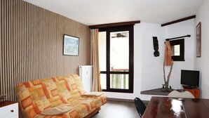 Ein Zimmer mit einer Couch, einem Holztisch, einem Fernseher und einer Heizung.