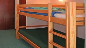 Ein Etagenbett mit Holzrahmen und grüner Bettwäsche.