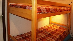 Una cama litera con ropa de cama escocesa y estructura de madera.