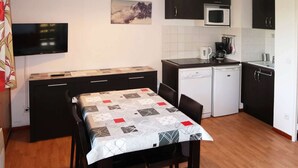 A compact kitchen with a dining area, featuring a microwave, coffee maker, and a small refrigerator.