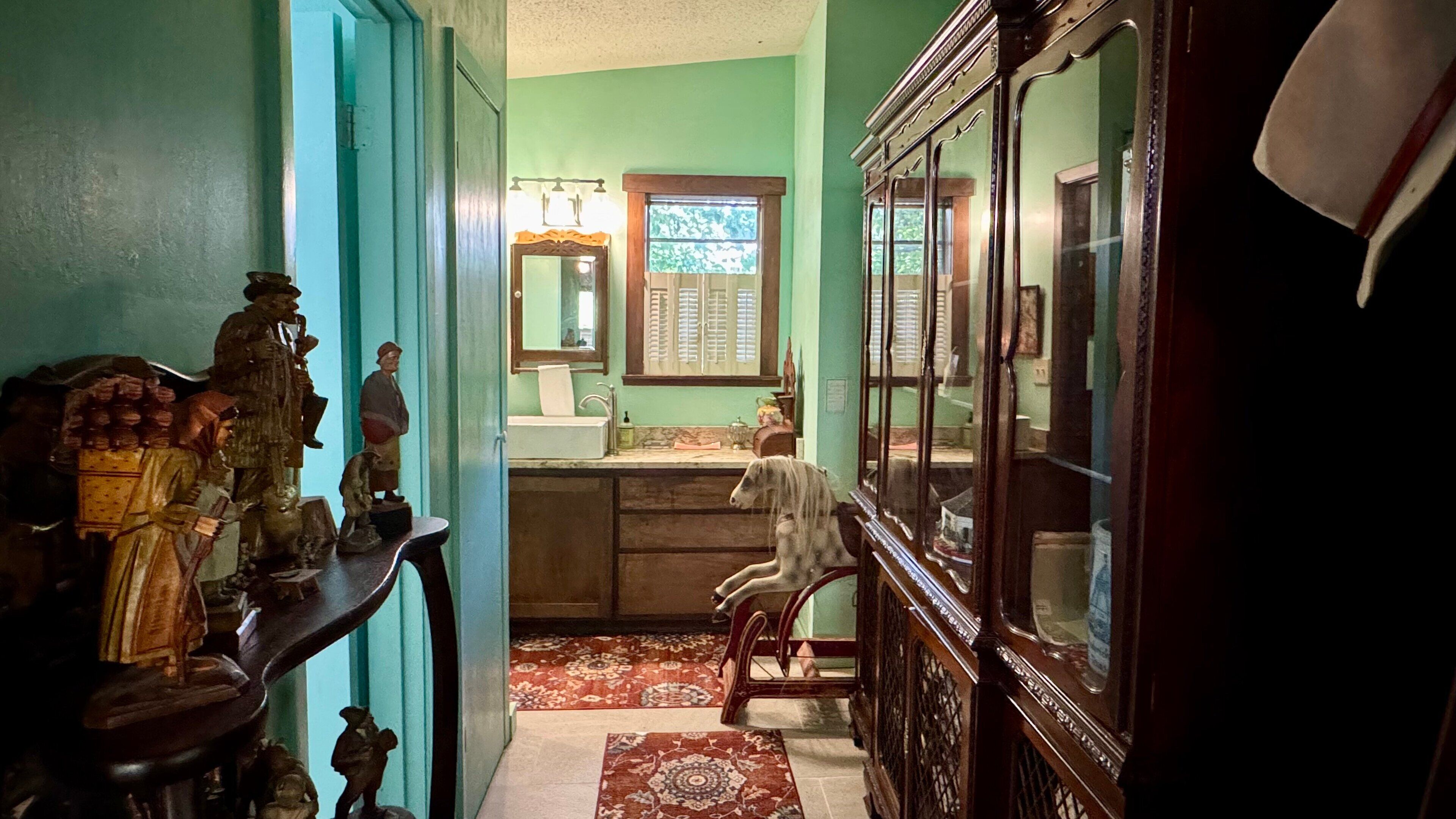 A hallway with a wooden bench, a mirror, and a window with shutters.