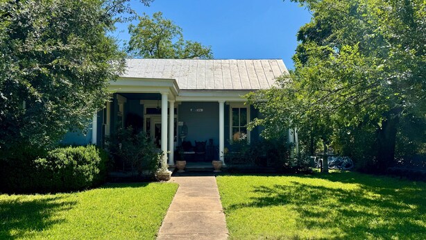 A house with a front porch, a pathway leading to the entrance, and a well-maintained lawn. - Alte Friedrichsburg | Historic Gem (Fredericksburg)