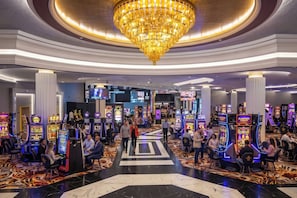 A casino with multiple gaming machines, a grand chandelier, and a central walkway.