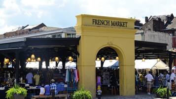 A market with a yellow archway labeled 'FRENCH MARKET,' various stalls, and people browsing.