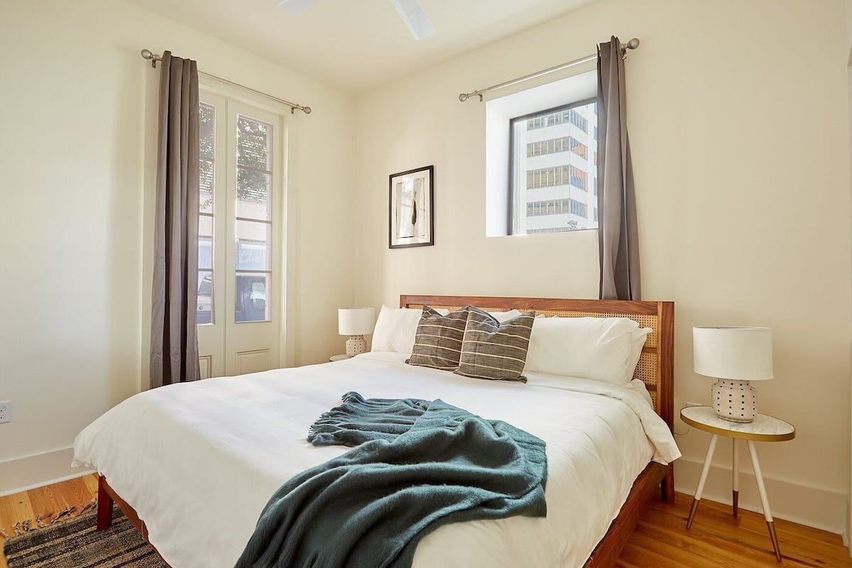Quarto com uma cama grande, duas mesas de cabeceira, janela com cortinas e um quadro na parede.