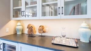 A kitchen with white cabinets, a granite countertop, and a tray with glasses and a bottle. - Stunning 4-Bedroom Private Penthouse Villa With Panoramic Views (Mountain Village)
