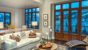A spacious living room with a large window, a sofa, a coffee table, and a fireplace. - Stunning 4-Bedroom Private Penthouse Villa With Panoramic Views (Mountain Village)
