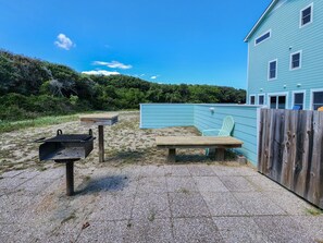 A backyard with a barbecue grill, a wooden bench, and a green Adirondack chair. - Aqua Vista - Beautiful 7 BR, 6.5 BA, Oceanside w/ Private Pool (Southern Shores)