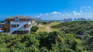 Ein Anwesen direkt am Strand mit einem mehrstöckigen Haus, einer sichtbaren Treppe und einem Weg zum Strand.