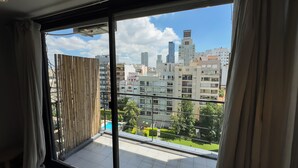 A room with a large window overlooking a cityscape with multiple high-rise buildings. - Soho Rentals (Buenos Aires)