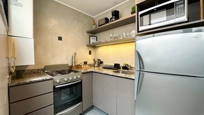 A modern kitchen with a gas stove, oven, microwave, and refrigerator. - Soho Rentals (Buenos Aires)