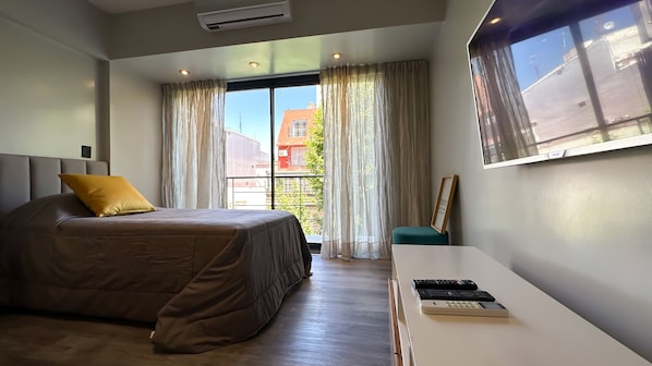 Habitación de hotel con cama, escritorio y ventana con cortinas.
