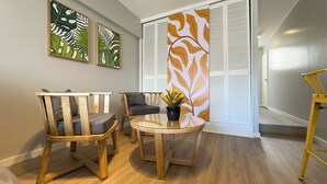 A room with two wooden chairs, a small round table, and a potted plant. There are two framed artworks on the wall and a sliding door with a leaf pattern. - Soho Rentals (Buenos Aires)