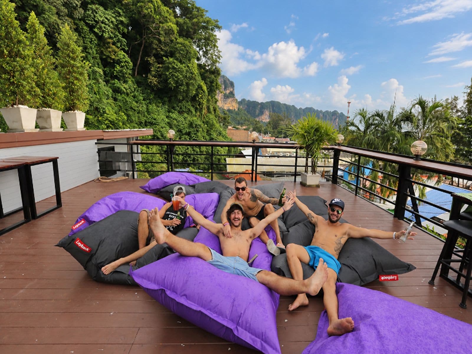 Un grupo de personas descansando en una terraza con vista al agua y vegetación.